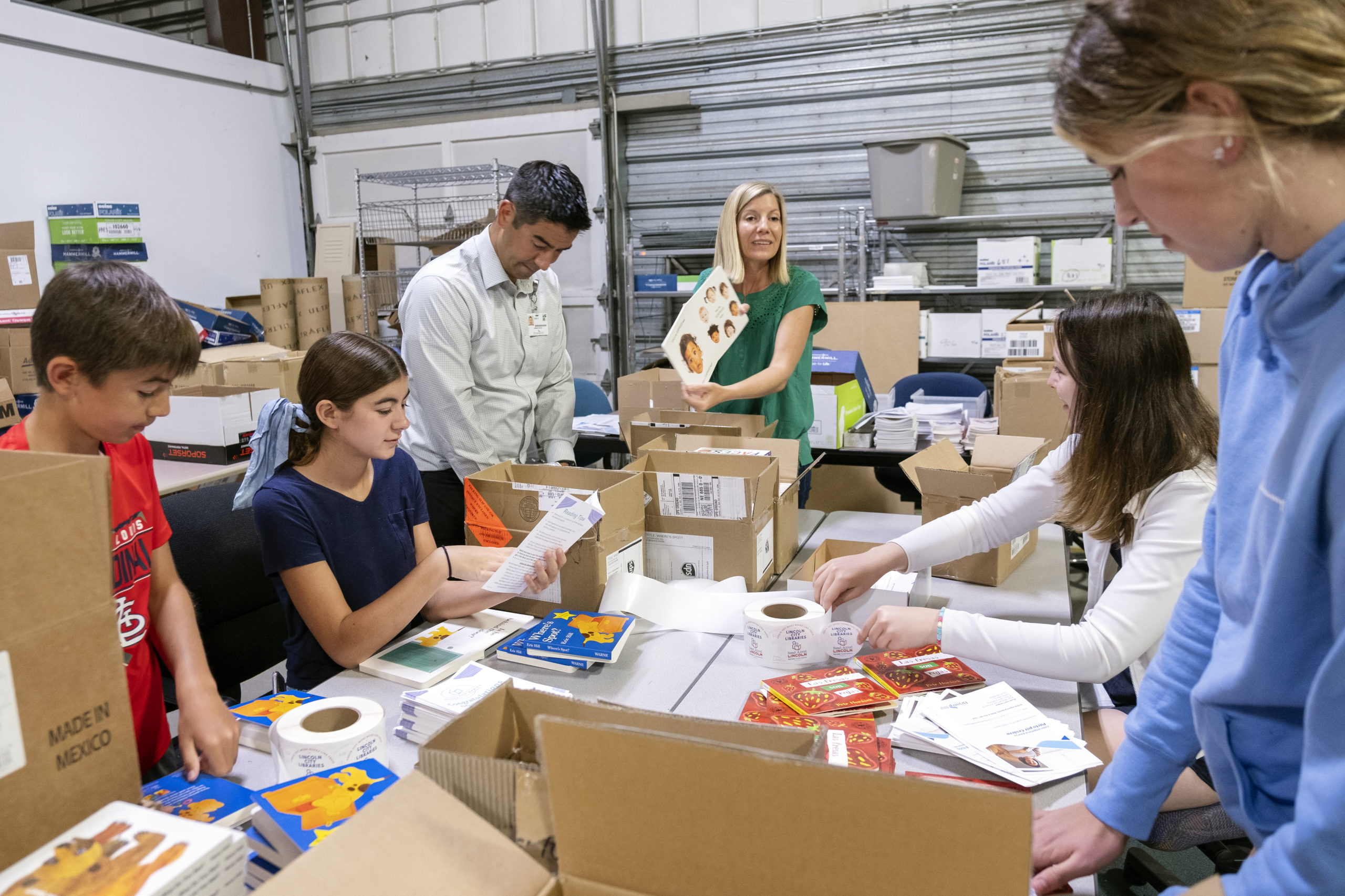 A group of volunteers work to repackage board books for distribution to local hospitals as part of the Books for Babies program.